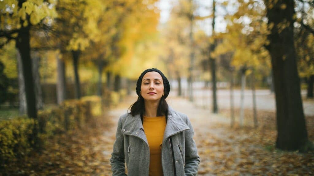 Une femme pratiquant la méditation en plein air, entourée d'arbres, illustrant les bienfaits de la méditation équivalant à 44 minutes de sommeil.