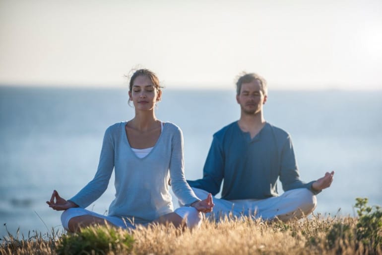 Une femme et un homme méditant ensemble, illustrant les multiples bienfaits de la méditation pour la santé mentale, tels que la réduction du stress,et l'amélioration de la mémoire.