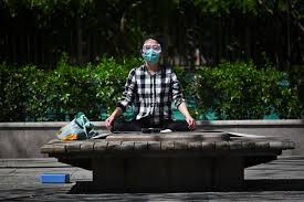 Un homme pratiquant la méditation avec un masque facial pendant le confinement, soulignant l'importance de méditer même dans des situations difficiles.