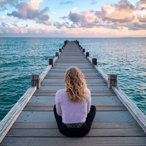 jeune femme pratiquant la meditation au bord de l’eau sur un ponton
