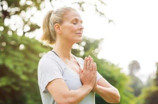 Une personne en position de méditation, ressentant un sentiment de calme et de sérénité, tandis que l'anxiété diminue et la santé cardiaque s'améliore.