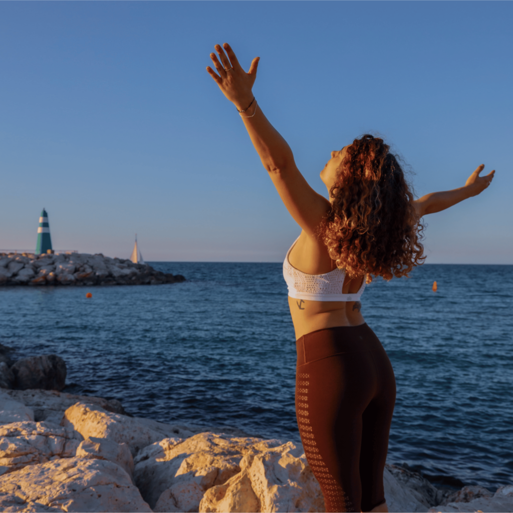 jeune femme épanouie ouvrant les bras face à la mer meditation