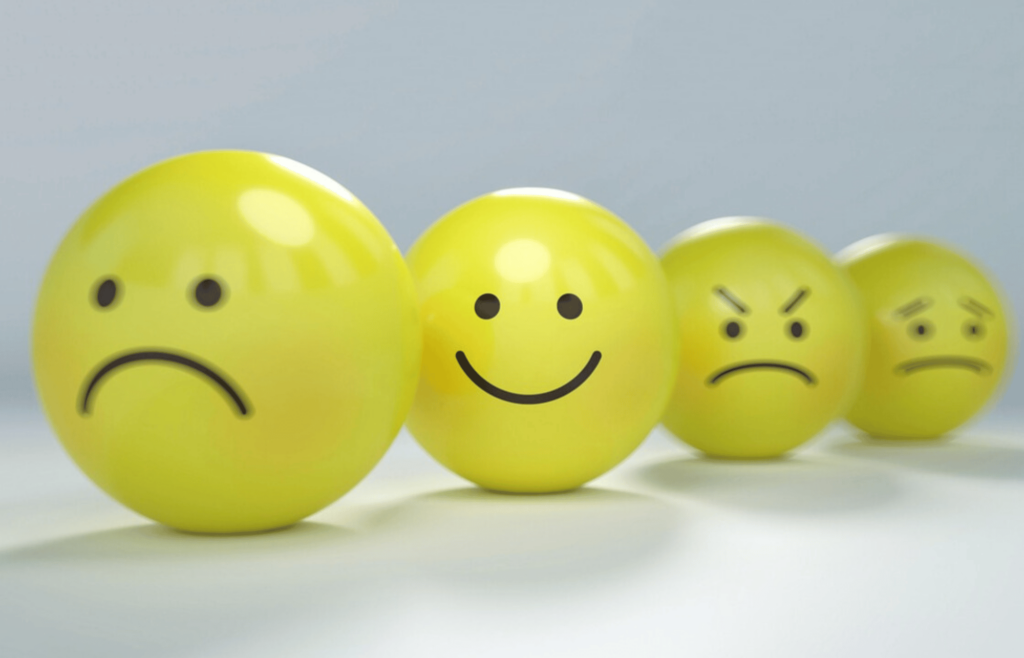 4 boules émoticônes jaunes avec une boule souriante etre optimiste dans la vie