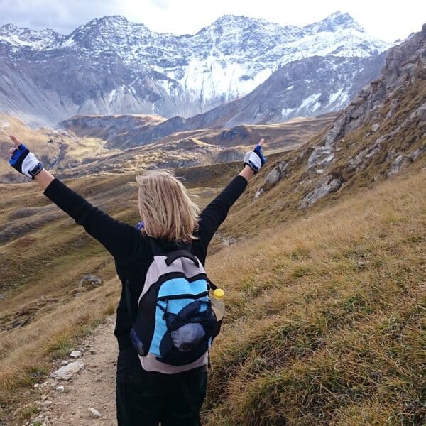 femme levant les bras en signe d'optimisme en haut d'une montagne