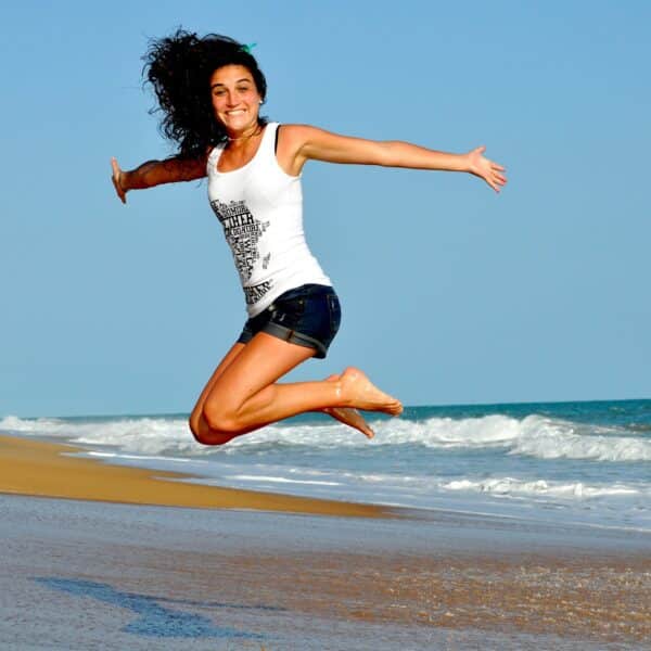 améliorer son bien-être physique grâce à la positivité femme souriante qui saute à la plage